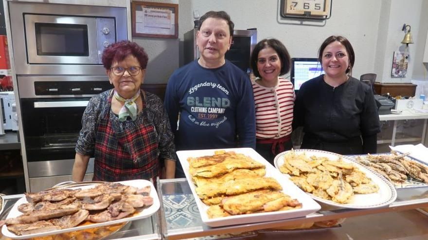 Cuatro personas del equipo de Taberna Alameda tras la barra, con bandejas de tortilla, chuletas y rebozados.